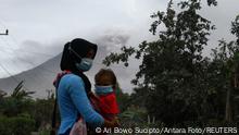 A woman carries her child wearing protective face masks to protect from volcanic ash following the eruption of Mount Semeru volcano in Supiturang, Lumajang, East Java province, Indonesia December 6, 2021, in this photo taken by Antara. Ari Bowo Sucipto/Antara Foto via REUTERS. ATTENTION EDITORS - THIS IMAGE WAS PROVIDED BY THIRD PARTY. MANDATORY CREDIT. INDONESIA OUT.