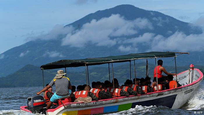 Army soldiers in a speed boat driving on a lake at the foot of Conchagua volcano
