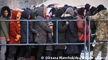 Das von der belarussischen Staatsagentur BelTA via AP zur Verfügung gestellte Handout zeigt Migranten, die in einem Logistikzentrum am Kontrollpunkt «Bruzgi» an der belarussisch-polnischen Grenze Schlange stehen, um warmes Essen zu bekommen. +++ dpa-Bildfunk +++