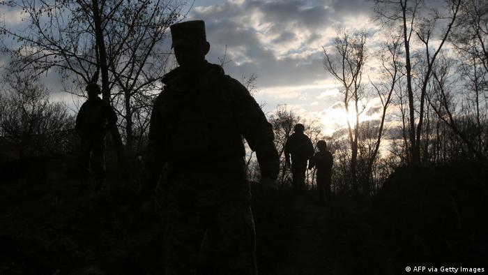 Ukrainian men in uniforms walk along rural area in Lugansk region