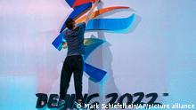 FILE - A crew member leaps to fix a logo for the 2022 Beijing Winter Olympics before a launch ceremony to reveal the motto for the Winter Olympics and Paralympics in Beijing on Sept. 17, 2021. The Beijing Winter Olympics open in just under two months and are now the target to a diplomatic boycott by the United States with others likely to follow. (AP Photo/Mark Schiefelbein, File)