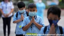 Students wearing face masks as part of health protocols pray during the first day of face-to-face classes at the Comembo elementary school in Makati city, Philippines on Monday, Dec. 6, 2021. Some schools in Manila were allowed to reopen with limited student capacity and reduced hours after months without face-to-face classes as COVID-19 cases continue to decline in the country while the government closely monitors the new omicron virus variant. (AP Photo/Aaron Favila)