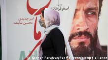 A woman walks past A Hero movie poster. A Hero is a 2021 Iranian film written and directed by Asghar Farhadi, and starring Amir Jadidi and Mohsen Tanabandeh. (Photo by Sobhan Farajvan / Pacific Press)