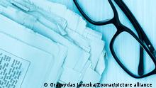A stack of newspapers with glasses. Blue toned image