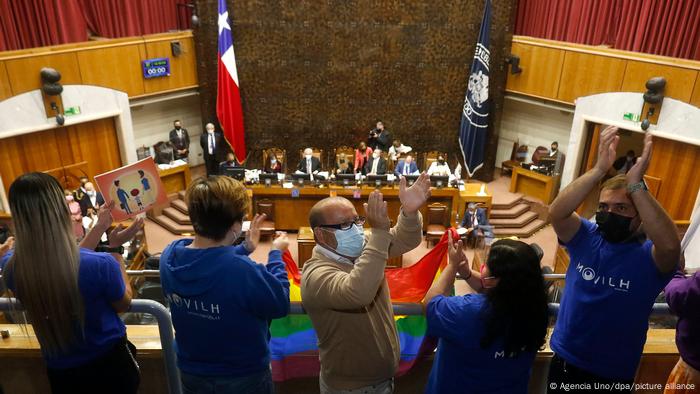People applaud holding a rainbow flag in Chile's congress building