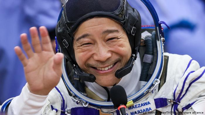 Space tourist Yusaku Maezawa waves as he wears a spacesuit