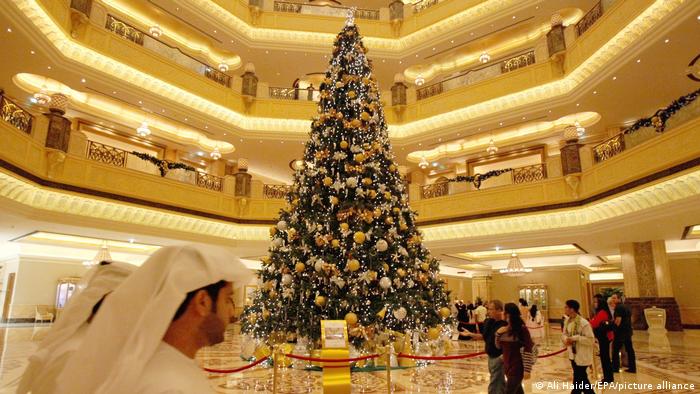 People walk past a Christmas tree at the Emirates Palace luxury hotel in Abu Dhabi, United Arab Emirates, 17 December 2010.