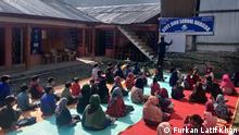 Children are sitting outside to be taught during the pandemic in Kashmir