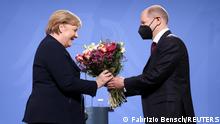Former German Chancellor Angela Merkel receives flowers from her successor, newly appointed German Chancellor Olaf Scholz, at the Chancellery in Berlin, Germany, December 8, 2021. REUTERS/Fabrizio Bensch