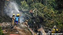 Firemen and rescue workers try to control the fire in the burning debris of an IAF Mi-17V5 helicopter crash site in Coonoor, Tamil Nadu, on December 8, 2021. - A helicopter carrying India's defence chief General Bipin Rawat crashed, the air force said, with a government minister at the scene saying at least seven people were dead. (Photo by AFP) (Photo by -/AFP via Getty Images)