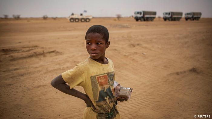 A Malian boy stands as a MINUSMA convoy pass by in the Gao region of Mali