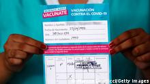 QUILMES, ARGENTINA - DECEMBER 29: Macarena Barrios, a member of the cleaning staff of Isidoro Iriarte Hospital, shows the certificate stating that she received a dose of 'Gam-COVID-Vac' also known as Sputnik V vaccine against coronavirus at Isidoro Iriarte Hospital on December 29, 2020 in Quilmes, Argentina. Argentine government begins today the campaign to apply the first 300,000 doses that arrived from Russia. (Photo by Marcos Brindicci/Getty Images)