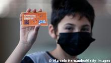 SANTIAGO, CHILE - OCTOBER 01: A student holds a National Vaccination Plan card after receiving the first dose of the Sinovac vaccine as part of the immunization plan against COVID-10 for children aged 6 to 11 at Alicante del Rosal school on October 1, 2021 in Santiago, Chile. Chile's Education Minister Ral Figueroa, Undersecretary of Public Health Paula Daza, Regional Education and Health secretaries Ricardo Villegas and Helga Balich take part in the vaccination process of children aged 6-11 and deliver a balance of the first week of immunization for this group with CoronaVac vaccine against COVID-19 at schools. (Photo by Marcelo Hernandez/Getty Images)