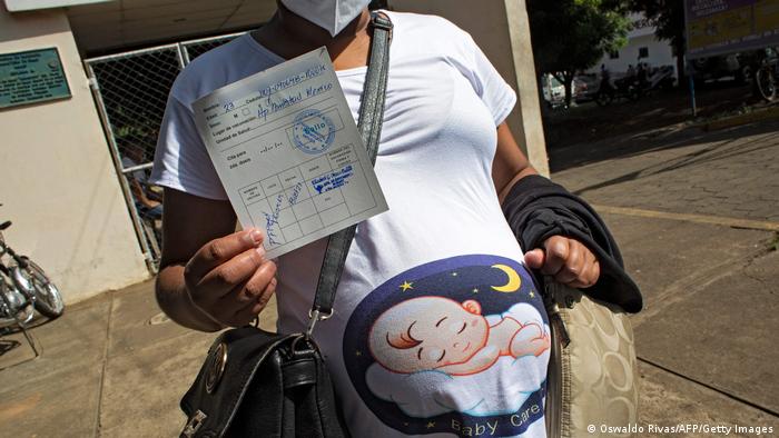  A pregnant woman, shows her vaccination card