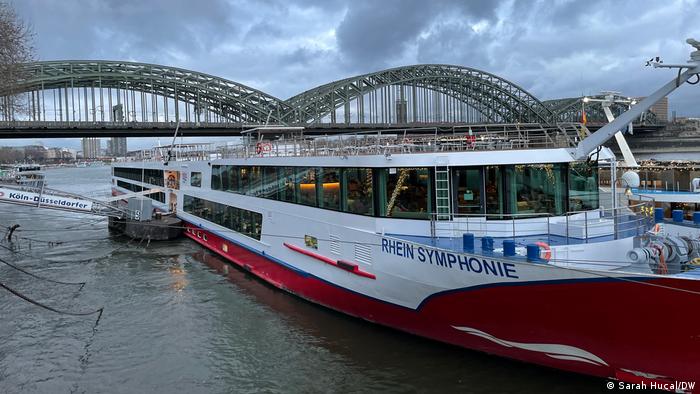 A long boat docked in Cologne with a bridge in the background