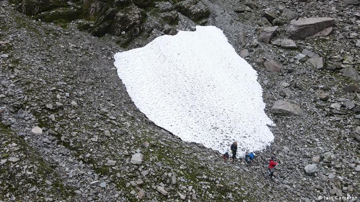 People standing around a snow patch 