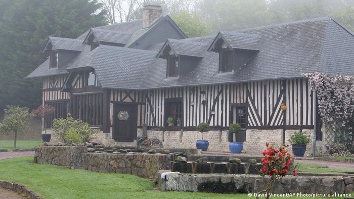 Ein typisch normannisches Fachwerkhaus, umgeben von grünem Gras und bunten Blumen