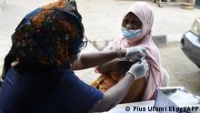 A picture taken on November 26, 2021 shows a health official administering to a woman a dose of Astrazeneca's Vaxzevria Covid-19 vaccine at Secretariat Community Central Mosque, Alausa, Ikeja in Lagos. - Fearing a surge in coronavirus cases over the Christmas travel season and wary of the emergence of new variants, Nigeria is turning to religious leaders, churches and mosques to push a mass vaccination campaign. (Photo by PIUS UTOMI EKPEI / AFP)