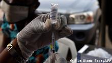 A health worker tries to load into a syringe a Vaxzevria Astrazeneca vaccine during the vaccination of Muslim faithfuls against coronavirus (COVID-19) at the Secretariat Community Central Mosque, Alausa, Ikeja in Lagos, on November 26, 2021. - Fearing a surge in cases over Christmas travel season and wary of the emergence of new variants, Nigeria is turning to religious leaders, churches and mosques to push a mass vaccination campaign. (Photo by PIUS UTOMI EKPEI / AFP)