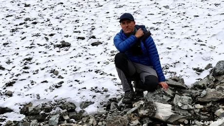 A man standing in front of a patch of snow 