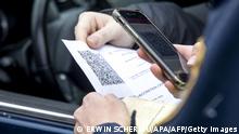 An Austrian police officer checks a driver's vaccination certificate on a smartphone during a traffic control in Graz, Austria, on November 15, 2021, during the ongoing coronavirus (Covid-19) pandemic. - Austria became the first EU country on November 15 to impose a lockdown on the unvaccinated and began inoculating children as young as five as the virus strengthens its grip on the continent. Unvaccinated people in Austria are only allowed to leave their homes for very specific reasons. They are still allowed to go to work, but there the 3G rule (vaccinated, recovered or tested) applies without exception. - Austria OUT (Photo by ERWIN SCHERIAU / APA / AFP) / Austria OUT (Photo by ERWIN SCHERIAU/APA/AFP via Getty Images)