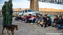 A group of about 30 Brazilian migrants, who had just crossed the border, sit on the ground near US Border Patrol agents, on the property of Jeff Allen, who used to run a brick factory near Mt. Christo Rey on the US-Mexico border in Sunland Park, New Mexico on March 20, 2019. - The militia members say they will patrol the US-Mexico border near Mt. Christo Rey, Until the wall is built. In recent months, thousands of Central Americans have arrived in Mexico in several caravans in the hope of finding a better life in the United States. US President Donald Trump has branded such migrants a threat to national security, demanding billions of dollars from Congress to build a wall on the southern US border. (Photo by Paul Ratje / AFP)