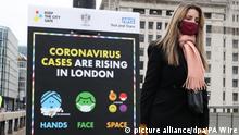 Eine Frau mit Mund-Nasen-Schutz geht an einem Corona-Informationsschild auf der London Bridge vorbei. Laut einer Studie sterben mehr schwarze und asiatische Menschen an dem Coronavirus als weiße, obwohl die Fallzahlen in der letzteren Gruppe höher sind. +++ dpa-Bildfunk +++
