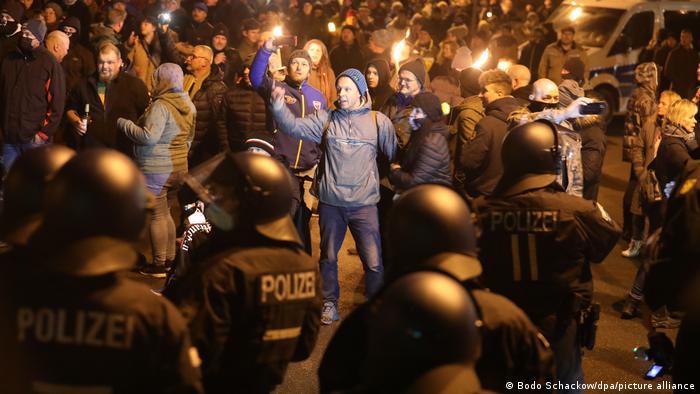 Anti-COVID protesters with torches, facing riot police in Greiz