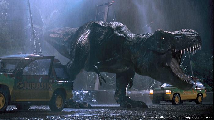 Film still from Jurassic Parc: A T-Rex roars among cars in the rain.