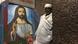 Ein orthodoxer Priester steht neben einem farbenfrohen Jesus-Gemälde in einer der Kirchen Lalibelas. Ein orthodoxer Priester steht neben einem farbenfrohen Jesus-Gemälde in einer der Kirchen Lalibelas.