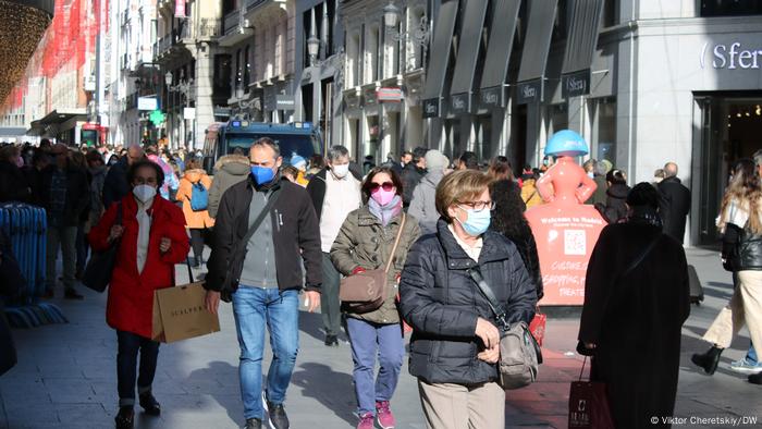 Personas que usan ropa protectora para la cara caminando por la calle comercial
