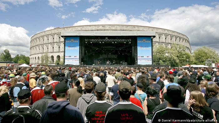 A concert takes place in front of the Congress Hall in 2006 with people watching a large stage.