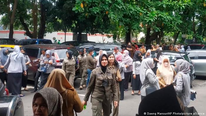 People wait outside after evacuating a government building following an earthquake in Makassar, South Sulawesi, Indonesia, Tuesday, Dec. 14, 2021.