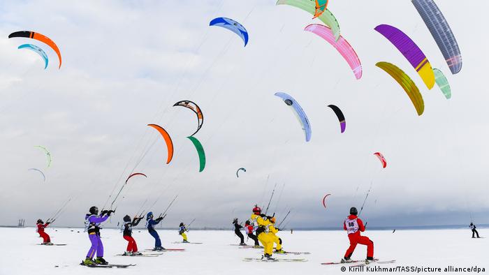 colorful kites pull skiers on snow