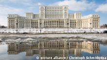 Der Palast des Parlaments spiegelt sich am 24.01.2017 in der rumänischen Hauptstadt Bukarest in einer Pfütze wieder. Der Parlamentspalast ist eines der flächenmäßig größten Gebäude der Welt. Foto: Christoph Schmidt/dpa