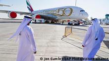Two Emiratis walk toward an Emirates Airbus A380 jumbo jet on display at the Dubai Air Show in Dubai, United Arab Emirates, Sunday, Nov. 14, 2021. The biennial Dubai Air Show opened Sunday as commercial aviation tries to shake off the coronavirus pandemic. (AP Photo/Jon Gambrell)