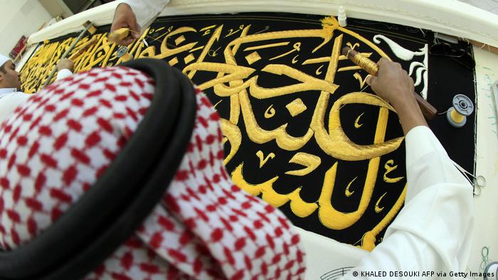 Des ouvriers saoudiens cousent des calligraphies islamiques en fil d'or sur un drap pour couvrir la Kaaba.