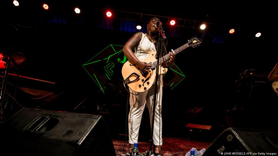 Eine Frau steht mit Gitarre auf der Bühne