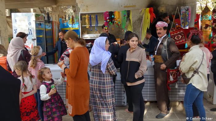 لقمان سليمان (الثاني من اليمين) أمام متجر بسيط لبيع الهدايا التذكارية في متحف لالش شمال العراق - صورة بتاريخ 30 أكتوبر 2021