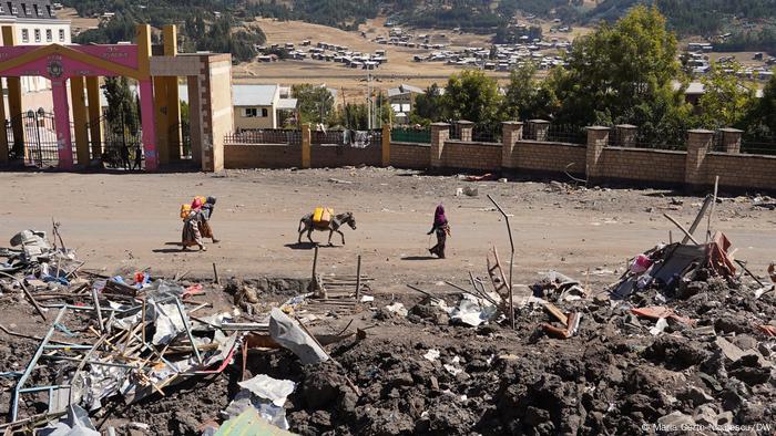 People walk amid ruins