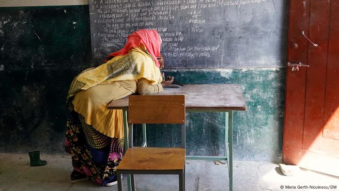 A woman leaning over a desk at a school
