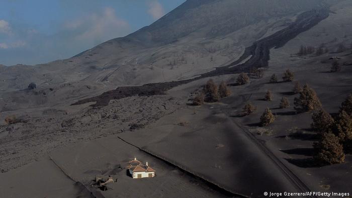 Ein fast komplett verschüttetes Haus ragt aus einem mit Lava und Asche bedeckten Hang heraus