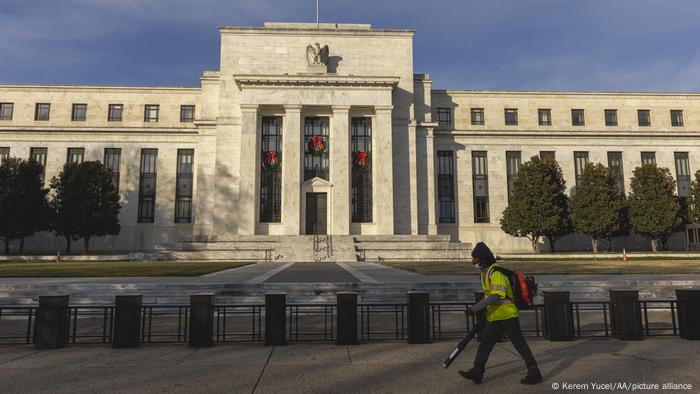 A landscape worker walks near the Federal Reserve building