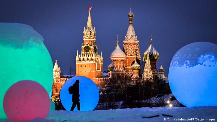Pedestrian silhouetted against Christmas decorations in front of St Basil's Cathedral, Moscow