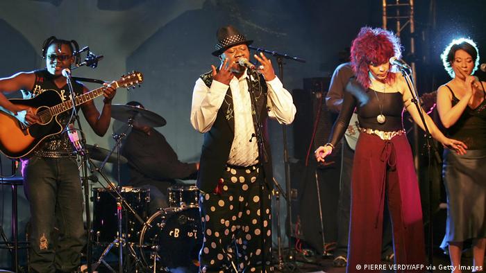 Papa Wemba steht mit Band auf einer Bühne