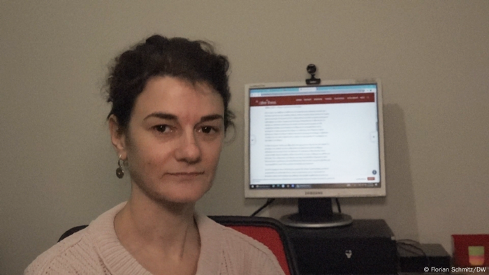 Woman faces the camera in front of a computer monitor.