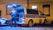 16.12.2021 Ein Polizist steht an einem Wagen vor einem Haus in Köln. Am Donnerstagmorgen gab es in der Domstadt Razzien gegen mehrere mutmaßliche Rechtsextremisten. Die Polizei suchte nach Material zum Bau von Bomben.