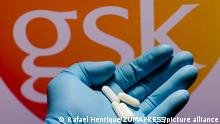 November 26, 2021, Brazil: In this photo illustration a GlaxoSmithKline (GSK) logo is seen on a screen and a hand holding pills. (Credit Image: © Rafael Henrique/SOPA Images via ZUMA Press Wire