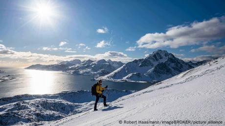 Skiwanderer vor Fjord und schneebedeckten Bergen auf den Lofoten, Norwegen