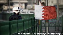 A riot policeman walks past a Bahraini flag placed on a gate by protesters during an anti-regime protest in the village of Abu Saiba, west of Manama, on May 17, 2013. Bahrain's main opposition accused government troops of raiding the home of the country's leading Shiite cleric Sheikh Issa Qassem, and warned that authorities will bear responsibility for this dangerous act. AFP PHOTO/MOHAMMED AL-SHAIKH (Photo credit should read MOHAMMED AL-SHAIKH/AFP via Getty Images)